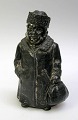 Sparebøsse af 
mand i metal, 
19. årh. Manden 
i stor frakke, 
hat og med en 
taske. H.: 13 
cm.