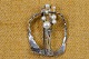 Broche af sølv 
kunstfærdigt 
udformet, 
hammerslået, 
skåret og 
dekoreret med 9 
perler f ...