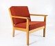 En lænestol i 
eg og rødt 
uldstof, 
designet af den 
anerkendte 
danske 
møbelarkitekt 
Hans J. Wegner 
...