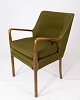 En armstol i 
birketræ med 
originalt 
mørkegrønt 
stof, af dansk 
design fra 
1950'erne, 
fremviser en 
...