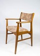 En armstol i 
teak og 
polstret med 
lyst stof, af 
dansk design 
fra 1960'erne, 
udstråler en 
tidløs ...