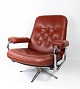 En armstol 
polstret med 
rødt læder og 
med et stel af 
metal, af dansk 
design fra 
1960'erne, ...