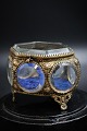 Gammelt Fransk 
6 kantet 
smykkeskrin i 
bronze og 
facetslebne 
glas med blåt 
velourstof i 
bunden og ...