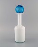 Otto Brauer for 
Holmegaard. 
Vase/flaske i 
hvidt mundblæst 
kunstglas med 
lyseblå kugle. 
...