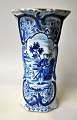 Delft blå - 
hvid vase, 
19./20. årh. 
Håndmalede 
dekorationer af 
hyrder på en 
mark. 8 kantet, 
...