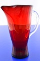 Holmegaard 
glasværk. Flot 
rød glaskande 
og hank af 
klart glas, 
højde 21 cm. 
Rummål 90.0 cl. 
Pæn ...