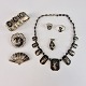 Smykkesæt 
bestående af 
halskæde, 
armbånd, to 
brocher, to 
ringe og et 
vedhæng. 
Smykkerne er af 
...