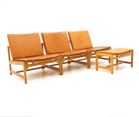 Arne Karlsen & Peter Hjorth: Satz von drei 
Lounge-Stühlen mit Schemel. Eiche mit patiniertem 
Leder. Ausgestellt in Milano 1961. L: 180cm. T: 
70cm. Hs: 30cm. H: 66cm