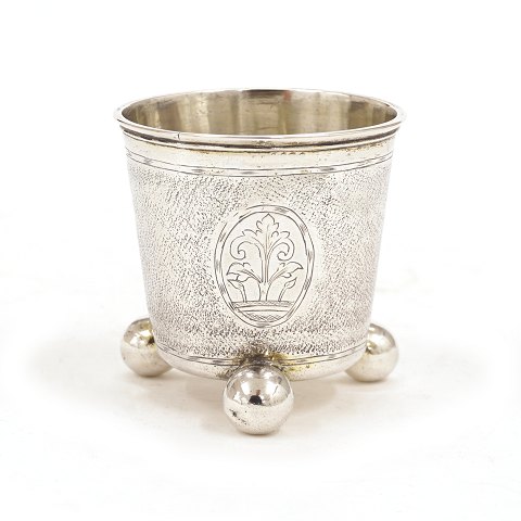 Nålepunlset sølvbæger på tre kuglefødder prydet 
med tre kartoucher, hvori spejlmonogram "CS". 
Fremstillet af Christian Lübecker, København, 
1722. H: 6,6cm. V: 59gr