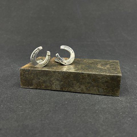A pair of ear clips with horseshoes