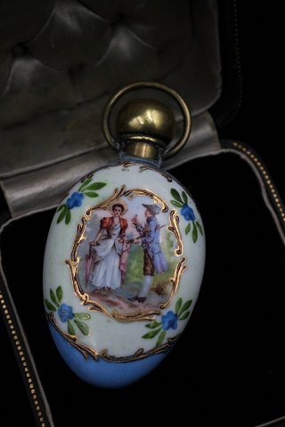 1800 tals parfume flaske i porcelæn med håndmalet motiv , guld dekoration og 
messinglåg. H:8,5cm. B:4cm.