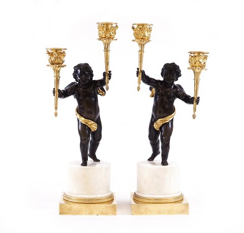 A Pair of early Empire fire gilt bronze candelabra 
with two putti each carrying two candlesticks. 
France circa 1795. H: 45cm