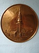 Hamret, rund 
kobberplakette.
Motiv: Budolfi 
Kirke, Aalborg.
Diameter - 25 
cm.
Nederst tekst 
- ...