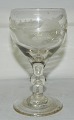 Antik glas med 
slibning på 
kummen med 
egeløv. Knap på 
stilken. 
Produceret 
omkring 1880.  
I ...