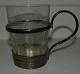 Teglas med 
holder i 
sølvplet. 
Fremstillet 
omkring 1900. 
Glasset er 
dekoreret. 
Diamantslibning 
i ...