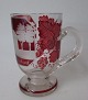 Bøhmisk glas, 
o. 1900 med 
rødt overfang 
og graveringer. 
Dekoration af 
bygning/slot 
med teksten: 
...