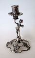 Miniature sølv 
lysestage, 19. 
årh. Med en 
lille engel.Fod 
med 
rosenmønster.  
H.: 7,6 cm. 
Stemplet.