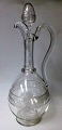 Vin kande i 
klart glas, 19. 
årh. Med 
slibninger og 
hank. H.: 32 
cm. Med prop. 