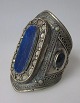 Afgansk arm 
smykke, 20. 
årh. Forsølvet 
metal med 
dekorationer og 
lapis lazuli. 
H.: 10 cm. 
Dia.: ...