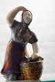 Figur i 
glaseret 
keramik med 
motiv af 
stående kvinde 
med kurv nr. B 
960
Design af 
Michael ...