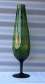 Grøn høj, vase 
på fod "6 
Hardy"
"Swedish art 
glass"
Mål  H.: 37cm  
Ø.: 9,5cm
Varenr.: ...