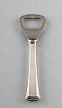 Evald Nielsen 
nummer 32, 
oplukker / 
flåskeåbner i 
sterlingsølv. 
Måler 12 cm.
Stemplet.
I ...
