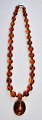 Neck chain with 
round amber 
pieces. With 
older brooch of 
...