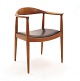 Hans J. Wegner, 1914-2007: The Chair i teak. Rygstykke med repareret brud. Se 
venligst foto. Stolen fremstår ellers stabil og brugbar. Sæde med sort læder