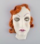 Art deco 
kvindeansigt i 
håndmalet 
glaseret 
keramik. 
Tyskland, 
1950'erne.
Måler: 18,5 x 
13 ...