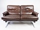 To personers sofa polstret med brunt patineret læder og stel i metal, designet af Arne Norell ...