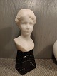 White marble 
bust of a young 
woman on black 
marble base. 
...