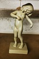Figur i keramik af stående pige. Venus Kalypogos. Dækket af creme-farvet glasurUdført af den ...