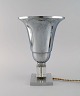 Bordlampe i 
aluminium og 
klart 
kunstglas. 
Fransk design, 
1940'erne.
Måler: 29 x 20 
cm.
I flot ...