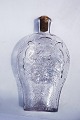 Lommeflaske i klart glas. Dekoreret med forskellige motiver i relief. Fremstillet omkring 1900. ...