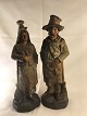 Zwei 
Terrakotta-
Figuren in Form 
eines armen 
Mannes und ...