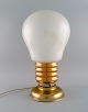 Stor bordlampe 
i messing og 
opalglas formet 
som elpære. 
1960'erne.
Måler: 49 x 27 
cm.
I flot ...