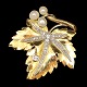Bladformet broche i 14 kt. guld og hvidguld, prydet med tre perler og talrige diamanter, i alt ...