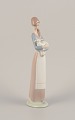 Lladro, 
Spanien. 
Porcelænsfigur 
af stående ung 
kvinde med lam 
i armene. 
Ca. ...