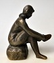 Dansk kunstner 
(20. årh.) Pige 
tager strømper 
på. Bronze. 
Monogrameret: 
HJ. Støbt hos 
Brdr Grage ...