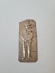 Votiv i sølv med motiv af en drengStemplet 800Mål 3,5 x 8 cm.