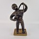Skulptur af en 
mand med en 
taske foran 
sig. Figuren er 
af bronze.
Foden er af 
messing og med 
...