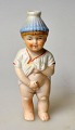 Bisquit figur - 
koldbemalet, 
19. årh. 
Tyskland. En 
lille tissende 
dreng med 
tophue. H: 10,5 
...