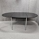 Ovalt spisebord 
med klap i 
begge ender. 
Sortlakeret 
bordplade med 
blanke stålben. 
Produceret i 
...