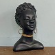 Afrikansk 
kvinde. Buste 
af sortmalet 
gips.
Øreringe af 
messing. 
H. 27 cm. B. 
18 cm. D. 16 
cm.
