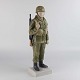 Figur i 
porcelæn nr. 
2444 med motiv 
af en soldat i 
kampuniform med 
gevær og fuld 
...