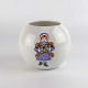 Kuglevase i 
porcelæn med 
motiv af 
vinterklædt 
pige med pakker 
samt juleklokke 
med rød sløjfe 
på ...