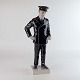 Figur i 
porcelæn 
udformet som en 
mand i mørkeblå 
uniform med 
kasket. Nr. 
2502
Producent Bing 
...