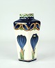 Denne elegante 
vase, model 
1044/102, er 
fremstillet i 
fajance og har 
en smuk 
firkantet form. 
Den ...