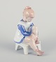 Bing og 
Grøndahl 
porcelænsfigur, 
siddende pige 
binder 
snørebånd.
Underglasur.
Midt ...