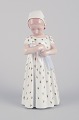 Bing & 
Grøndahl, 
porcelænsfigur 
af pige med 
dukke. 
Underglasur.
Design af Mary 
Ingeborg ...